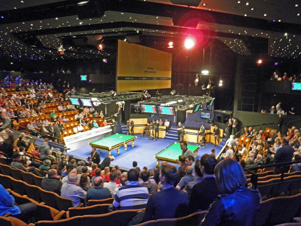 Picture from the World Snooker Championship 2013 taken from the back of the seats with a view of the audience and the two snooker tables in the middle